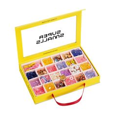 a yellow box filled with lots of different types of candies on top of a white surface