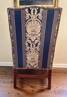 an ornately decorated chair sits in front of a painting on the wall behind it