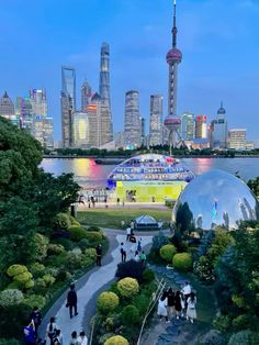 people are walking around in front of the water and cityscape with skyscrapers