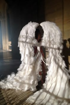 a woman standing in front of a white angel wings