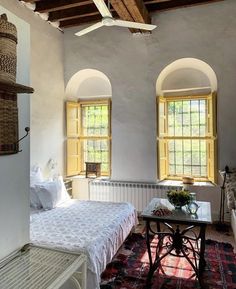 a bedroom with two windows and a bed in the corner, next to a rug on the floor