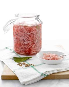 a glass jar filled with shredded meat next to a bowl of seasoning on top of a cutting board