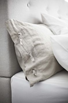 a close up of a bed with pillows and sheets on it's headboard