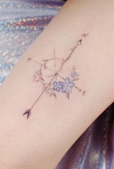 an arrow and flowers tattoo on the right arm, with stars in the sky above it