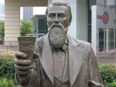 a statue of a man holding a book in his right hand and wearing a suit