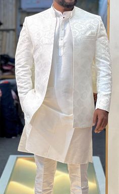 a man in a white outfit standing on a runway