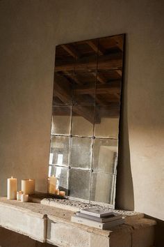 a mirror sitting on top of a wooden table next to candles and a candle holder