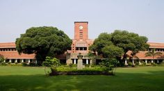 the building has many trees in front of it and is surrounded by lush green grass