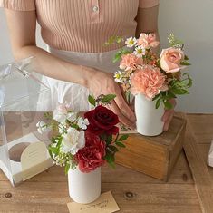 a woman is arranging flowers in vases on a wooden table with an apple watch