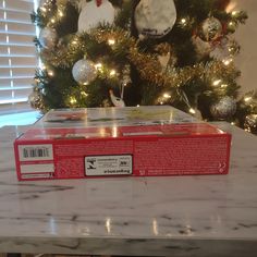 a red box sitting on top of a counter next to a christmas tree