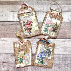 four tags with flowers on them are hanging from strings in front of a wooden wall