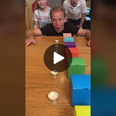 a man making a face while sitting at a table with two children and an adult