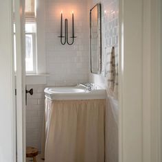 a bath room with a sink a mirror and two candles on the wall next to it