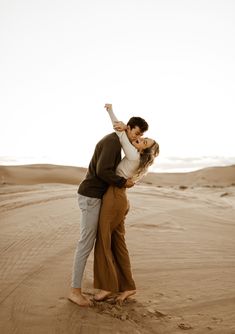 a man and woman are kissing in the middle of an open desert area with sand dunes behind them