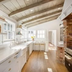 a large kitchen with white cabinets and wood beams on the ceiling is pictured in this image