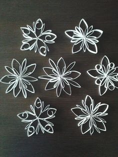 six white paper flowers on a black surface