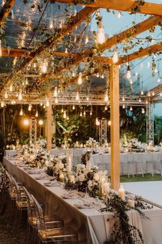 an outdoor dining area with tables, chairs and chandeliers in the middle of it