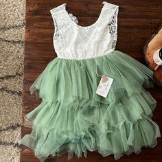 a green and white dress sitting on top of a wooden floor next to a shoe