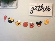 a paper garland with mickey mouse ears and pumpkins hanging on a wall next to a sign that says gather