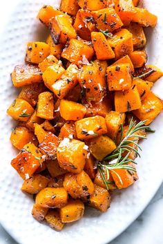 a white plate topped with roasted carrots and herbs