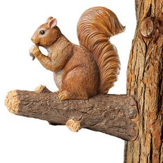 a statue of a squirrel sitting on top of a tree branch next to a piece of wood