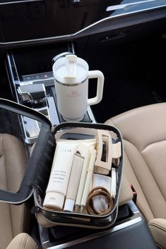 an open suitcase sitting on top of a car seat next to a cup and other items