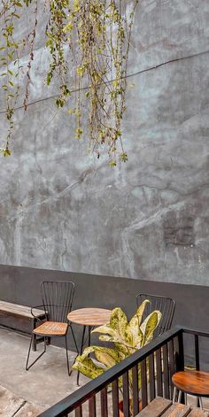 two wooden chairs sitting next to each other on top of a cement floor covered in plants