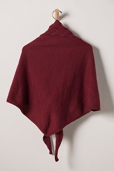 a red ponchy hanging on a wall next to a coat rack with a wooden hanger