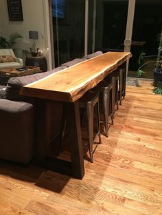 a wooden table sitting in the middle of a living room next to couches and windows