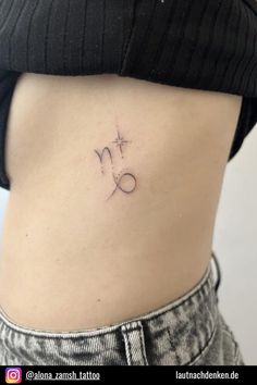 the back of a woman's stomach with an astro sign tattoo on it