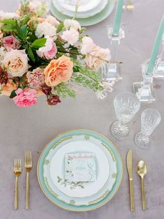 the table is set with plates, silverware and flowers