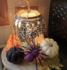 two pumpkins sitting on top of a table next to a glass jar filled with glitter