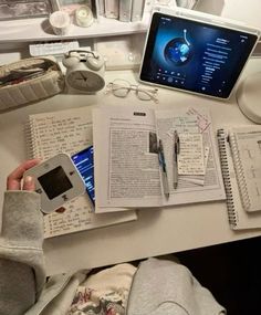 an open book sitting on top of a desk next to a laptop computer and cell phone