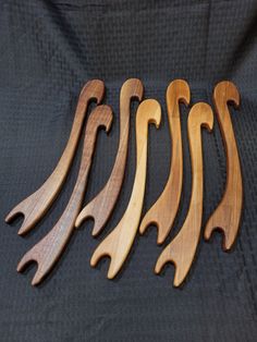 five wooden spoons are lined up on a black cloth