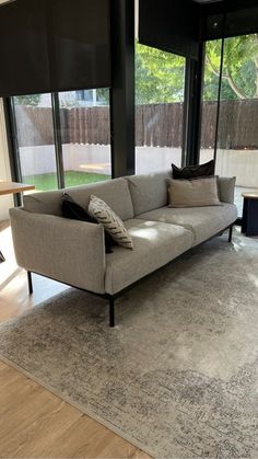 a modern living room with large windows and an area rug in front of the couch