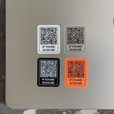 there are four different stickers on the back of a silver laptop computer that says if found scan me