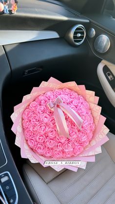 a car dashboard with a pink rosette cake in the center and ribbon on it