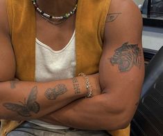 a man with tattoos on his arms and chest sitting in front of a computer desk