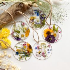 four glass coasters with flowers on them sitting next to some dried grass and twigs