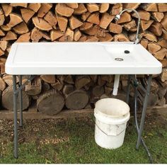 a white sink sitting on top of a pile of firewood next to a bucket