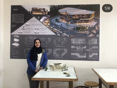 a woman standing in front of a table with a building on the wall behind her