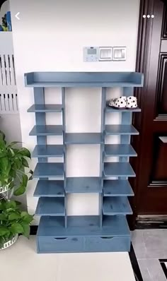 a blue book shelf sitting on top of a tiled floor next to a potted plant