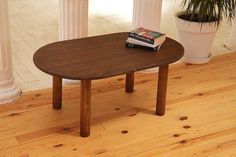 a wooden table sitting on top of a hard wood floor next to a potted plant