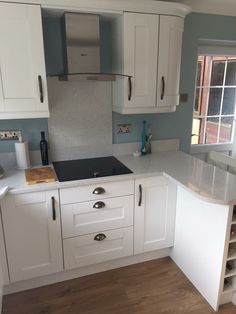 a kitchen with white cabinets and wood floors