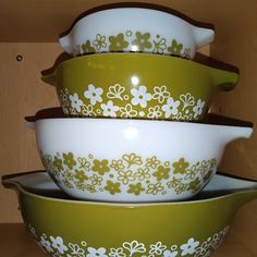 four green and white bowls stacked on top of each other in front of a wooden wall