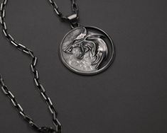 a silver necklace with a wolf head on it's side and a black chain around the neck