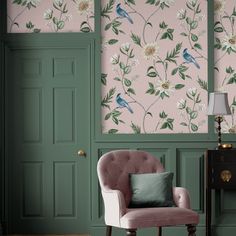 a pink chair sitting in front of a green wall with flowers and birds on it