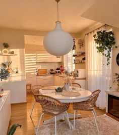 a white table and chairs in a room with wood flooring, potted plants on the far wall