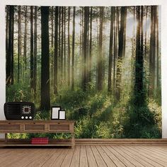 a room with a wooden floor and a wall hanging on the wall that has a forest scene in it