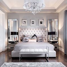 a large white bed sitting in a bedroom under a chandelier